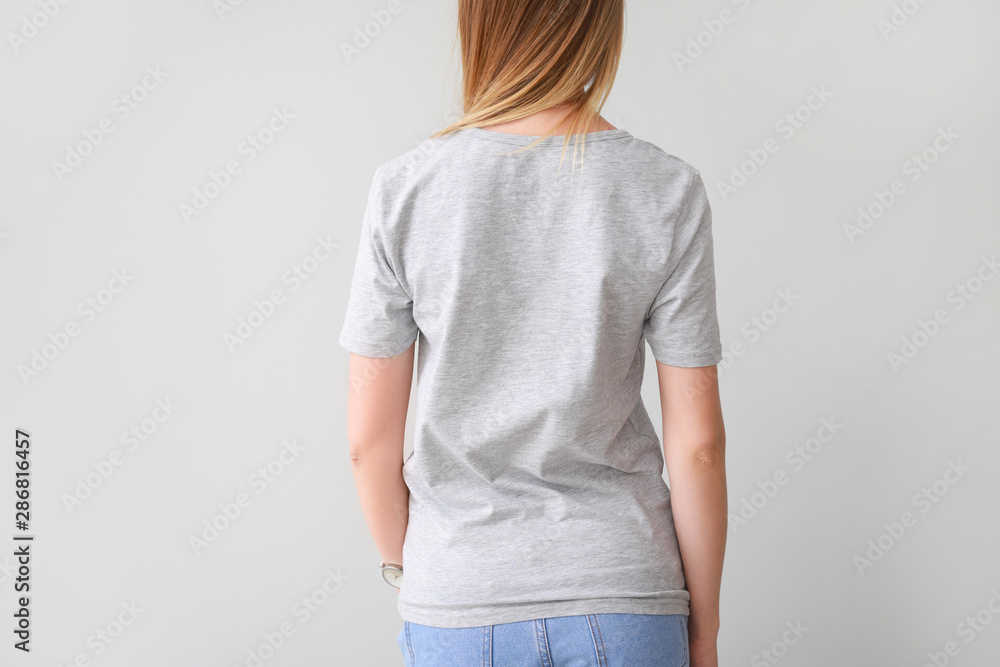 Woman in stylish t-shirt on light background, back view