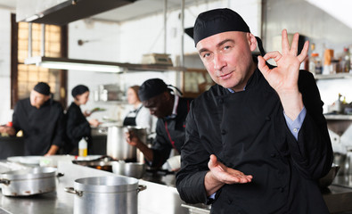 Wall Mural - Positive male cook with cooked dish in restaurant kitchen