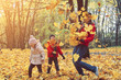 © sommersby - happy family walking in sunny park and throws orange maple leaves. mother with kids enjoying autumn weather outdoors
