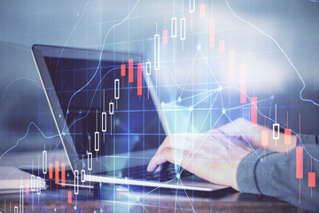 Double exposure of man's hands writing notes of stock market with forex graph background. Concept of research and trading.