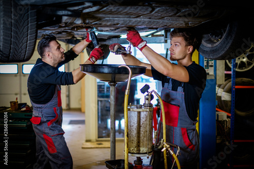 Fotografía Car mechanic changes oil in a workshop