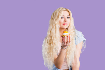 Wall Mural - Happy lovely curly young woman holding birthday cupcake with candle