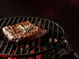 Wall Mural - Cooking beef meat steak on hot grill barbecue with fire flams and smoke on black background.