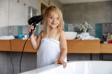 Wall Mural - Cute girl with a hairdryer in the bathroom