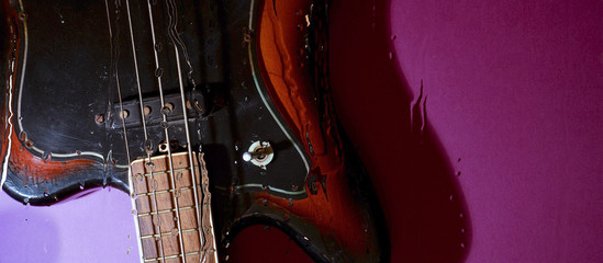 bass guitar behind the glass with water drops . color background