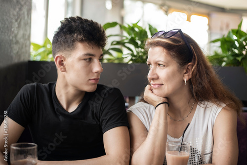 Pretty Woman Sitting With Her Teenage Son In A Cafe And Talking