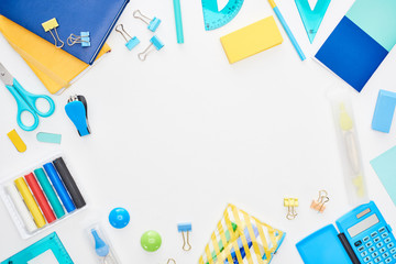 Top view of blue and yellow scattered school supplies isolated on white