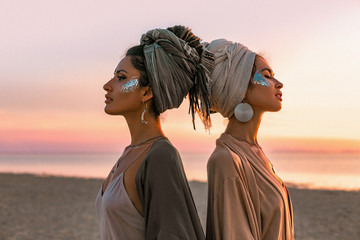 Wall Mural - two young beautiful girls in turban on the beach at sunset