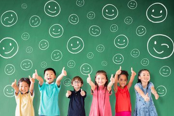 Wall Mural - happy Multi-ethnic group of school children standing in classroom with emotion face icon