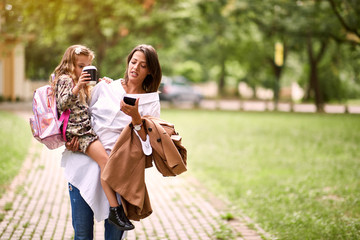 Wall Mural - young business mother taking child to primary school..