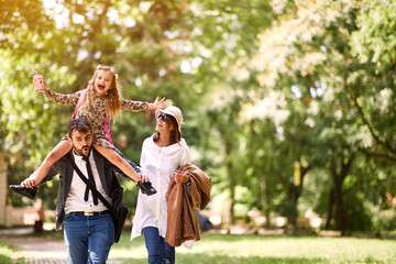 Wall Mural - Mother and father with their daughter after school have fun together.