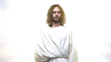 Wall Mural - Merciful Jesus looking into camera against shining background, grace of Lord