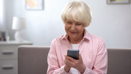 Extremely glad senior woman scrolling photos on smartphone, social network