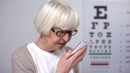 Wall Mural - Elderly female trying to read on smartphone, small font, poor vision problem