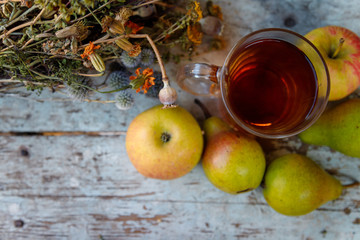 autumn harvest composition with apples pears cup of tea and dry healing herbs on wooden blue table background