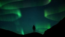Aurora Borealis Green Fluor Northern Lights And Silhouette Man Watching. Winter Landscape With Polar Weather In Arctic, Norway,Canada,Finland,Iceland, Sweden. Starry Night Sky Scenery Background 4k