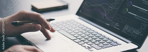 Fotomural Businessman is using laptop and analysing the financial information at his office
