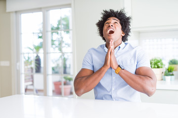 Sticker - African American business man begging and praying with hands together with hope expression on face very emotional and worried. Asking for forgiveness. Religion concept.