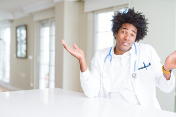 Sticker - African American doctor man at the clinic clueless and confused expression with arms and hands raised. Doubt concept.