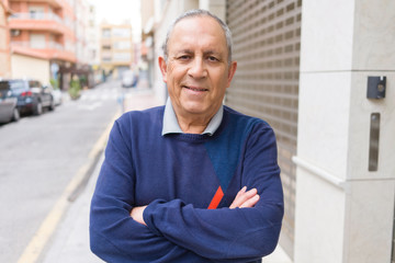 Wall Mural - handsome middle age senior man smiling cheerful, happy and positive with crossed arms at the city to