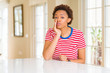 © Krakenimages.com - Young beautiful african american woman at home hand on mouth telling secret rumor, whispering malicious talk conversation