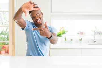 Poster - Handsome african american man wearing casual t-shirt at home smiling making frame with hands and fingers with happy face. Creativity and photography concept.