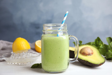 Mason jar of tasty avocado smoothie on white wooden table