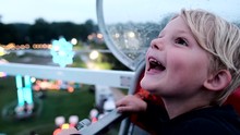 Toddler Smiling While Riding Ferris Wheel. Handheld. Blur
