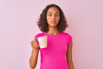 Canvas Print - Young brazilian woman drinking cup of coffee standing over isolated pink background with a confident expression on smart face thinking serious