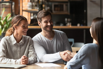 Happy young couple handshake insurer bank manager make financial deal