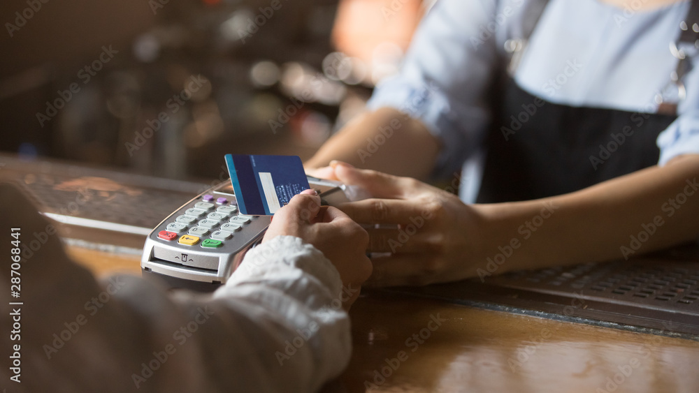 Female customer holding credit card near nfc technology on counter - obrazy, fototapety, plakaty 