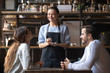 © fizkes - Smiling waitress hold notepad take order serving couple customers
