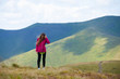© Андрей Репетий - Happy young girl hiker in a red sweater standing on the background of mountain while her hair fluttering in the wind