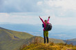 © Андрей Репетий - Young woman hiker standing on the top of mountain with raised hands feeling seccess and freedom