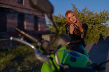 Wall Mural - Beautiful young girl with a fashionable hairstyle and red lips poses next to motorcycle