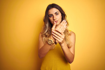 Poster - Young beautiful woman wearing t-shirt over yellow isolated background Suffering pain on hands and fingers, arthritis inflammation