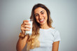 © Krakenimages.com - Young beautiful woman drinking a glass of milk over white isolated background with a happy face standing and smiling with a confident smile showing teeth