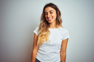 Sticker - Young beautiful woman wearing casual white t-shirt over isolated background looking away to side with smile on face, natural expression. Laughing confident.