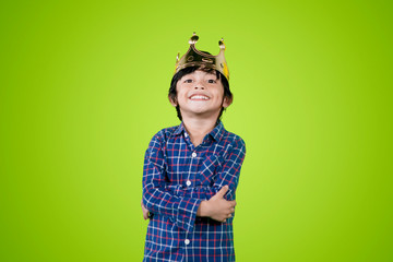 Confident little boy wearing a crown in the studio