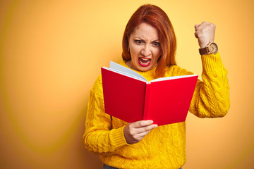 Sticker - Young redhead teacher woman reading red book over yellow isolated background annoyed and frustrated shouting with anger, crazy and yelling with raised hand, anger concept