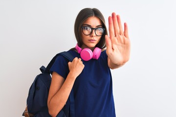 Wall Mural - Young student woman wearing backpack glasses headphones over isolated white background with open hand doing stop sign with serious and confident expression, defense gesture