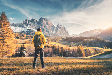 Wall Mural - young man with backpack standing on the hill against the mountains at sunset in autumn. landscape wi