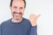 © Krakenimages.com - Handsome senior man over isolated background smiling with happy face looking and pointing to the side with thumb up.