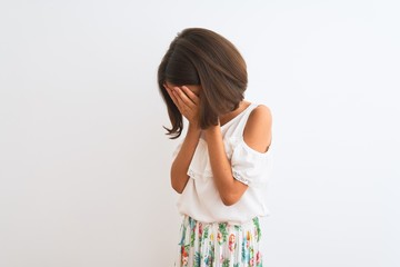 Young beautiful child girl wearing casual dress standing over isolated white background with sad expression covering face with hands while crying. Depression concept.