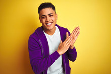 Young Brazilian Man Wearing Purple Sweatshirt Standing Over Isolated Yellow Background Clapping And Applauding Happy And Joyful, Smiling Proud Hands Together