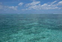 Wide Green Sea Horizon Under White Cloud Sunny Blue Sky In Maldives. Coral Reefs Under Shallow Clear Water