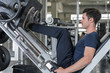 © CasanoWa Stutio - Handsome man lowering weight training legs on leg press machine and working out in the fitness gym