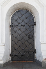 Vintage metal openwork door in a white stone wall.