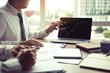 © wutzkoh - Businessman point to the laptop looking graph of the company financial statements in the computer screen and together analysis the work room.