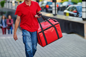 Pizza delivery man carries breakfast, lunch, dinner for consumers. Man of takeaway with red insulated food bag in hand. Courier delivering food. Express food delivery service from cafes, restaurants